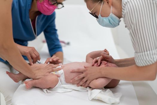 Baby beeing vaccinated by pediatrician in presence of his mother. Preventive vaccination against Diphtheria, whooping cough, tetanus, hepatitis, haemophilus influenzae, pneumococcus, poliomyelitis.