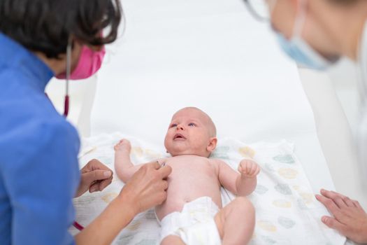 Baby lying on his back as his doctor examines him during a standard medical checkup.