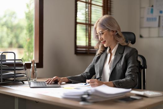 Charming businesswoman working on laptop at her workplace at modern office