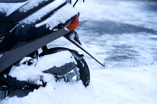 The scooter is covered with snow. Bad weather for riding a motorcycle.