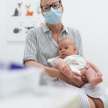 Mother holding her baby boy at medical appointment at pediatrician office