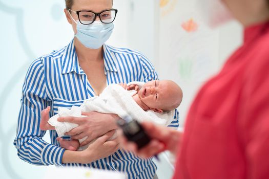 Mother holding her baby boy at medical appointment at pediatrician office