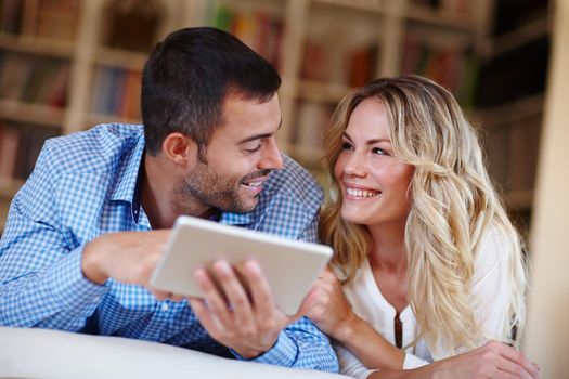 Technology bringing couples together. a young couple sitting at home using a digital tablet