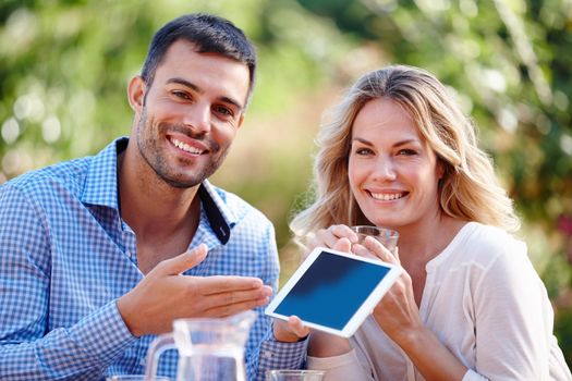 The best travel accessory. Portrait of a young couple using a digital tablet while eating breakfast