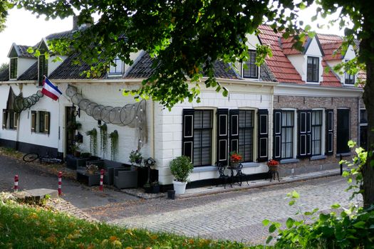 Elburg, the Netherlands - Sept. 9 2022 Typical dutch houses with tiled roofs, black door and shutters on the windows. Fishing nets show this is a historical fishing village. The Dutch flag upside down is a sign of protest.