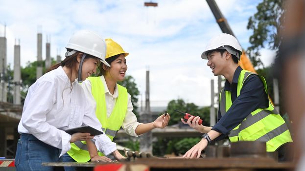 Engineer team in safety helmet and reflective jackets are planning development details and inspecting construction site.