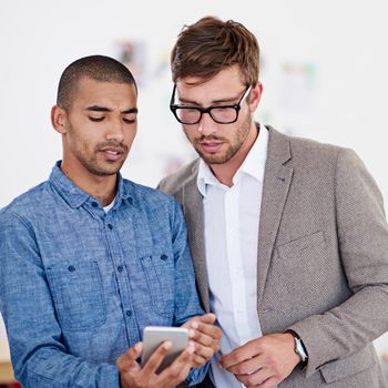 I like what Im seeing. two coworkers standing in an office looking at a digital tablet