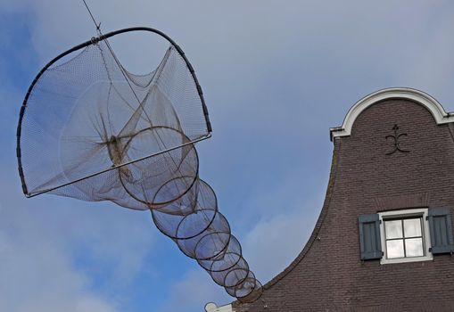 Part of a clock gable of a house. On this house is a fishing net  (hoop net or fyke) connected. These nets are used in Elburg, the Netherlands, to beautify the main street