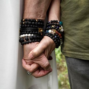 Senior man en woman holding hands. They wear lava stone and other breaded bracelets.