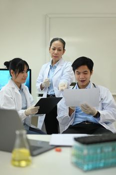 Experienced senior woman scientist and young researcher analyzing test samples, discussing about new test results in laboratory.