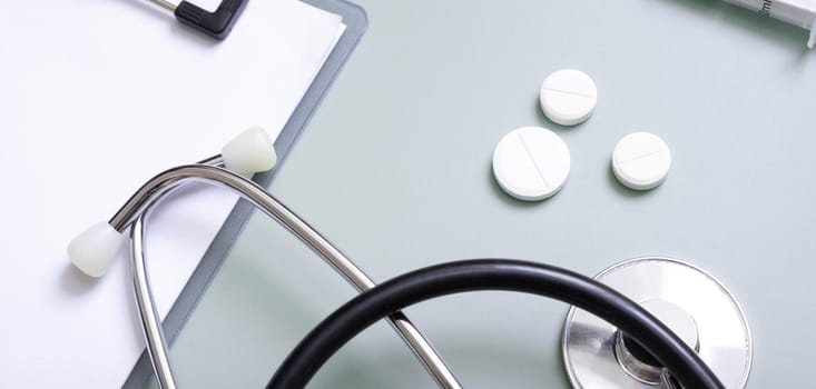 Banner with stethoscope, pills and tablet at doctor's workplace on colored background top view.