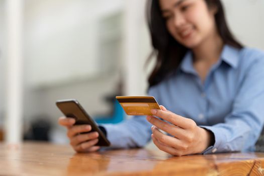 Young woman holding credit card and using smart phone for online shopping. Online payment shopping concept.