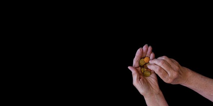 Big banner, black background with copy paste. The hands of an elderly woman with arthritis count coins in her hands. The concept of poverty, benefits for the elderly, old age