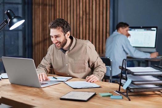 smiling business man working on a laptop in a night office. concept of overtime work.