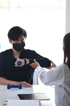 Young male patient doing physical exercises with his therapist.