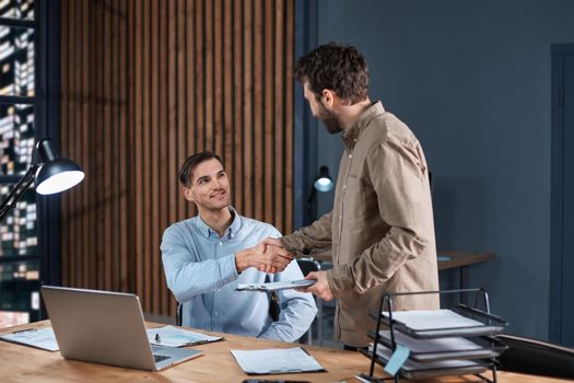 business colleagues shaking hands at the workplace. concept of overtime work.