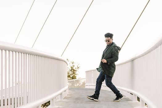 young stylish black man with white earphones and sun glasses dancing happy outdoor in the city and having some fun, lifestyle and technology concept, copy space for text