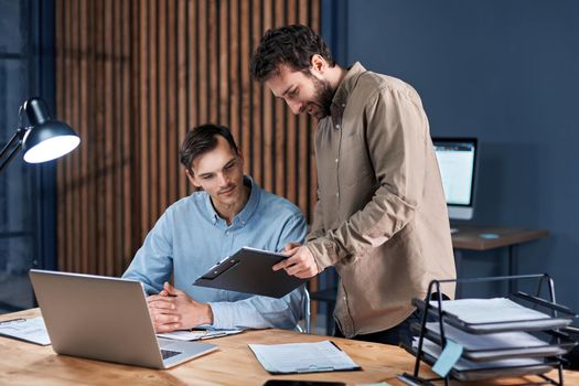 colleagues discussing a business document late at night in the office . concept of overtime work.