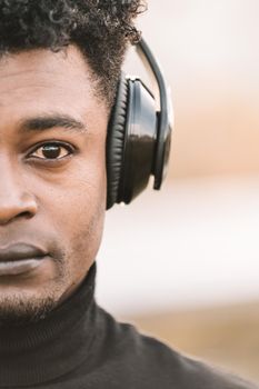 vertical half head portrait of a serious african black man listening music with the headphones, technology and lifestyle concept