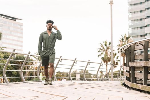 cool young african black man calling by phone while walks in a park outdoors in the city, lifestyle and technology concept, copy space for text