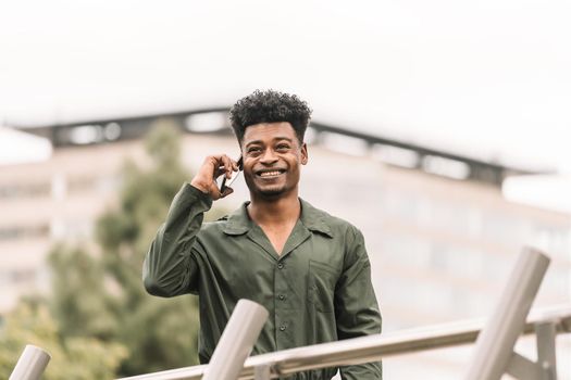 cool young african black man calling with the smart phone while walks in a park outdoors in the city, lifestyle and technology concept, copy space for text