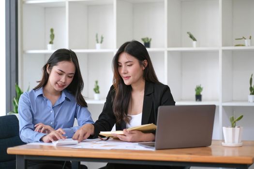 Two Young Asian businesswoman discuss with new startup project Idea presentation, analyze planning and financial statistics and investment market at office..