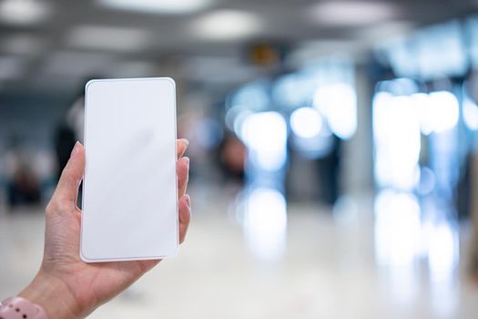 Hand holding smartphone with blank screen white Isolated on blur airport background.