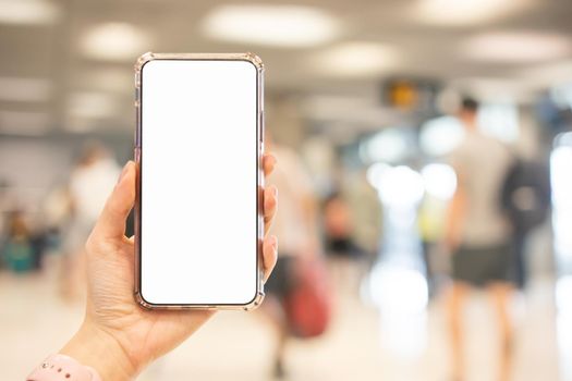 Hand holding smartphone with blank screen white Isolated on blur airport background.