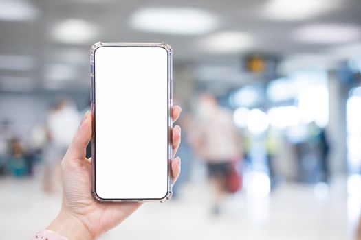 Hand holding smartphone with blank screen white Isolated on blur airport background.