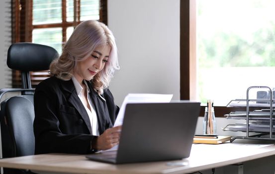 Smiling asian business woman sitting in a modern office..