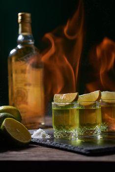 Bottle and glasses of tequila with lime on a wooden table. Traditional Mexican alcoholic beverage. Alcoholic cocktail with lime. The gin drink is served in glasses and limes 
