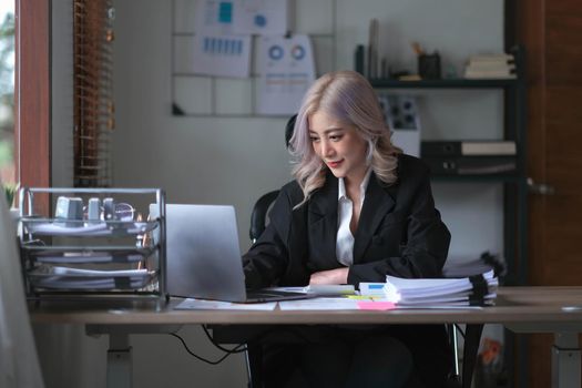 Smiling asian business woman sitting in a modern office..