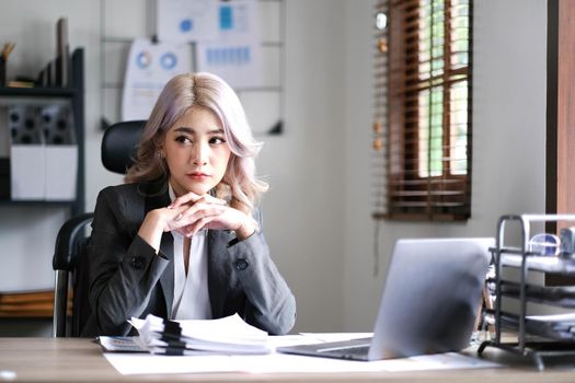 Image of an Asian woman who is tired and overthinking from working with a tablet at the office..