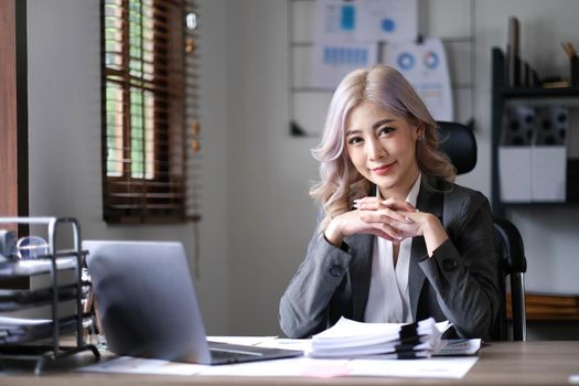 Charming Asian woman working at the office using a laptop Looking at the camera..