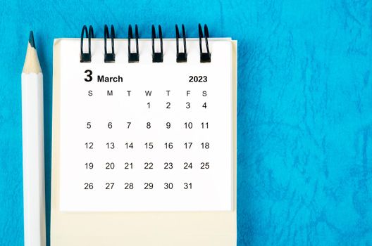 March 2023 Monthly desk calendar for 2023 with pencil on blue background.