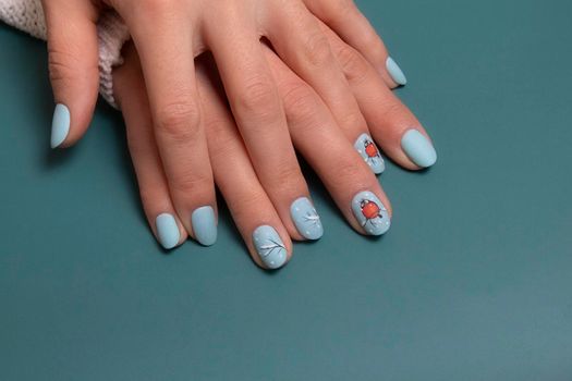 Female hands with winter snow manicure with stickers under a matte top.