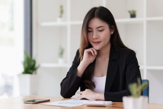 Asian Business woman working to analyze technical price graph and indicator with business team talking by cell phone. account or saving money or insurance concept.