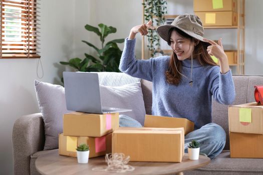 Startup small business entrepreneur SME, asian woman packing cloth in box. Portrait young Asian small business owner home office, online sell marketing delivery, SME e-commerce telemarketing concept.