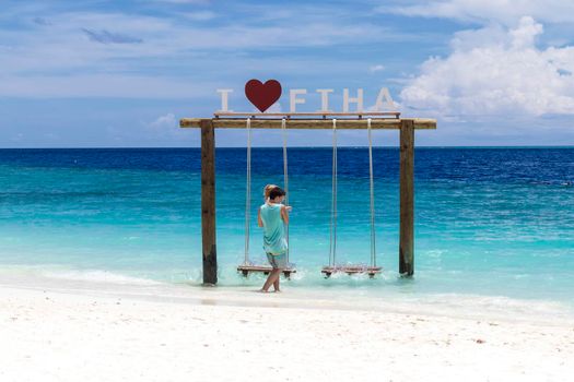 Male, Maldives 04.24.2021 - Kids are playing on the swing at Fihalhohi island resort beach