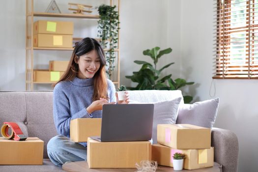 Starting Small business entrepreneur freelance, Portrait young woman working at home office, BOX, smartphone, laptop, online, marketing, packaging, delivery, b2b, SME, e-commerce concept.
