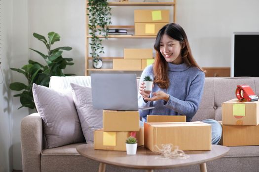 Starting Small business entrepreneur freelance, Portrait young woman working at home office, BOX, smartphone, laptop, online, marketing, packaging, delivery, b2b, SME, e-commerce concept.