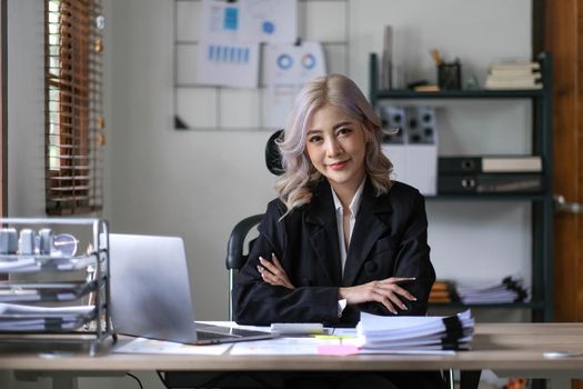 Asian businesswoman with arms looking at camera in the office..