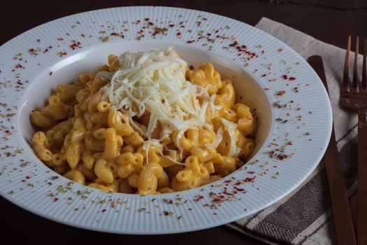 Mac and cheese, american style macaroni pasta with cheesy sauce on dark rustic table, top view. High quality photo