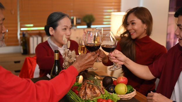 Group of people celebrating Christmas, thanksgiving party dinner and clinking glass of wine. Holidays and celebration concept.