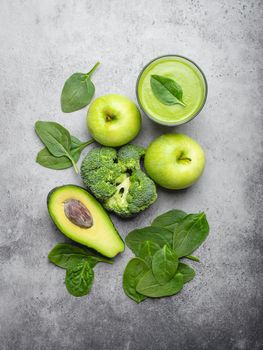 Ingredients for making green healthy smoothie, broccoli, apples, avocado, spinach over gray stone background. Clean eating, detox plan, vitamins, diet and weight loss concept. Close up, top view