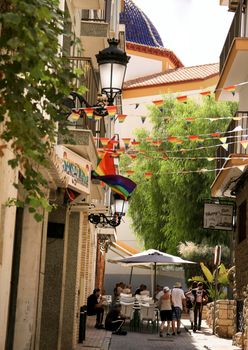 Benidorm, Alicante, Spain- September 11, 2022: Narrow Street and facades adorned with colorful rainbow flags for The Gay Pride in Benidorm