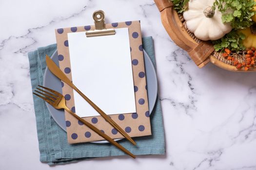 Autumn flat lay with blank tablet with cutlery and decorative pumpkins on marble background top view.