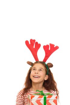 Little Santa girl in a Christmas hat ertical shot of a pretty young curly haired girl wearing raindeer antlers laughing joyfully holding her Christmas preent looking at the copyspace above her isolated