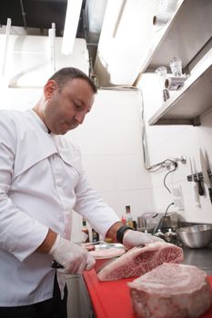 Vertical shot of a male chef working at his kitchen, cutting beef