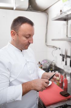 Vertical shot of a professional chef opening quail egg with a knife